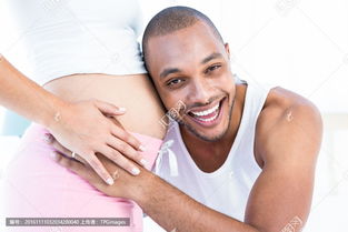 男人微笑着趴在怀孕妻子的肚子上