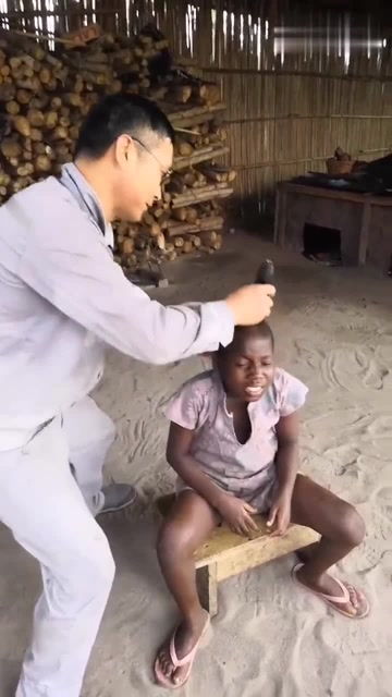 给非洲女孩子理头发,看着孩子的表情,是害怕电推子吗 
